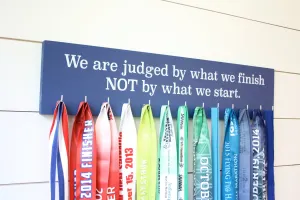 Medal Display - We are judged by what we finish NOT by what we start. - Large - Running / Triathlon / Ultra / Obstacle Race
